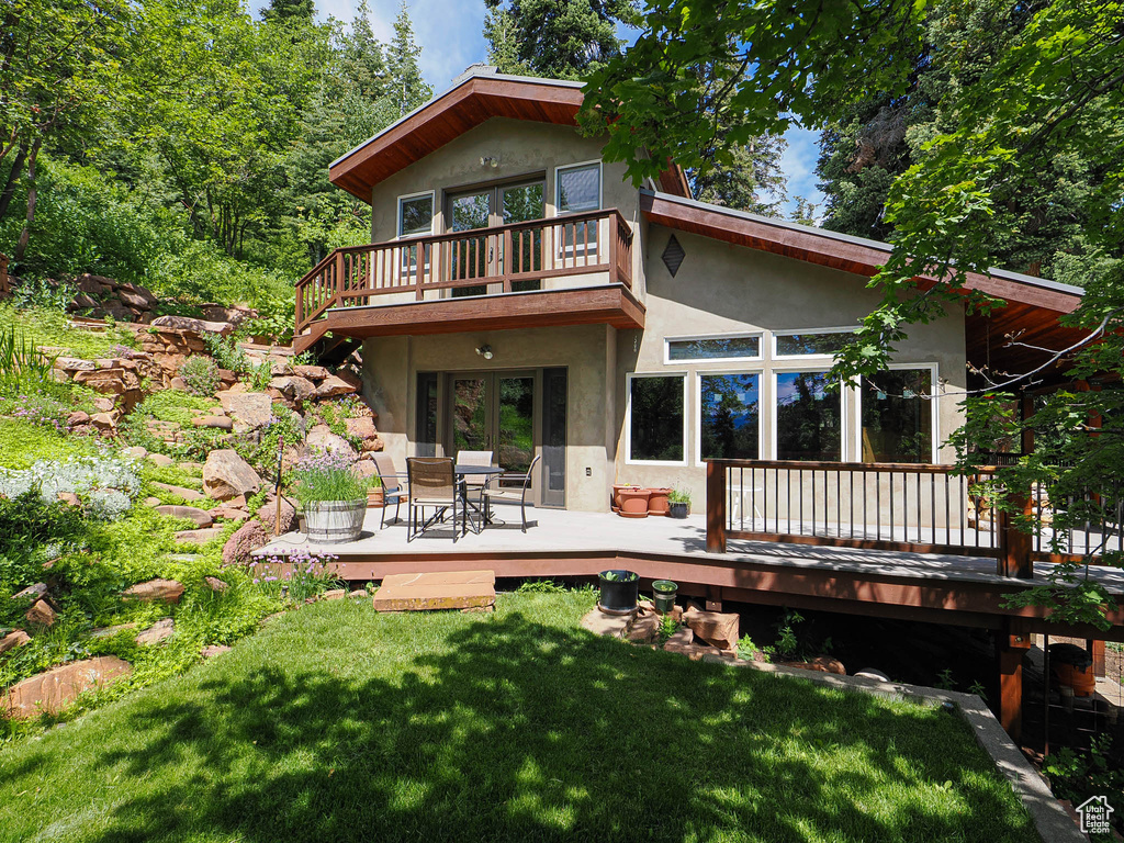 Back of property with stucco siding, a wooden deck, a lawn, and french doors