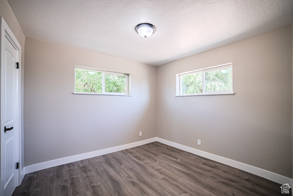 Spare room featuring dark wood-type flooring and baseboards