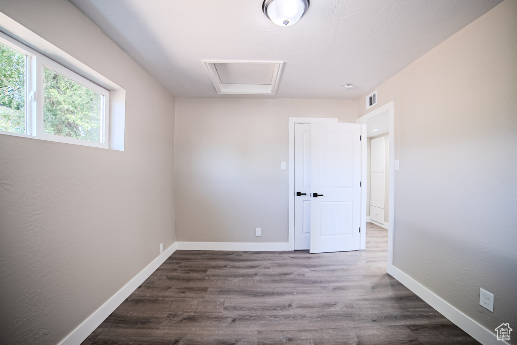Spare room featuring dark wood-style flooring and attic access