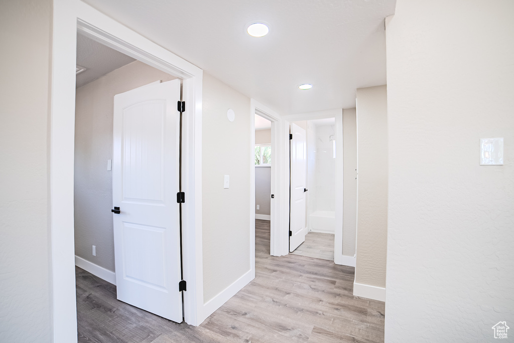 Hallway with light wood-style flooring and recessed lighting