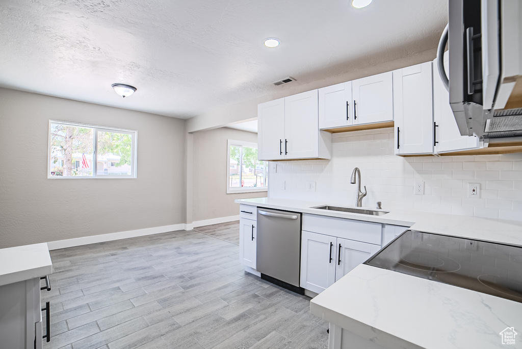 Kitchen featuring appliances with stainless steel finishes, decorative backsplash, light wood-style floors, white cabinets, and recessed lighting