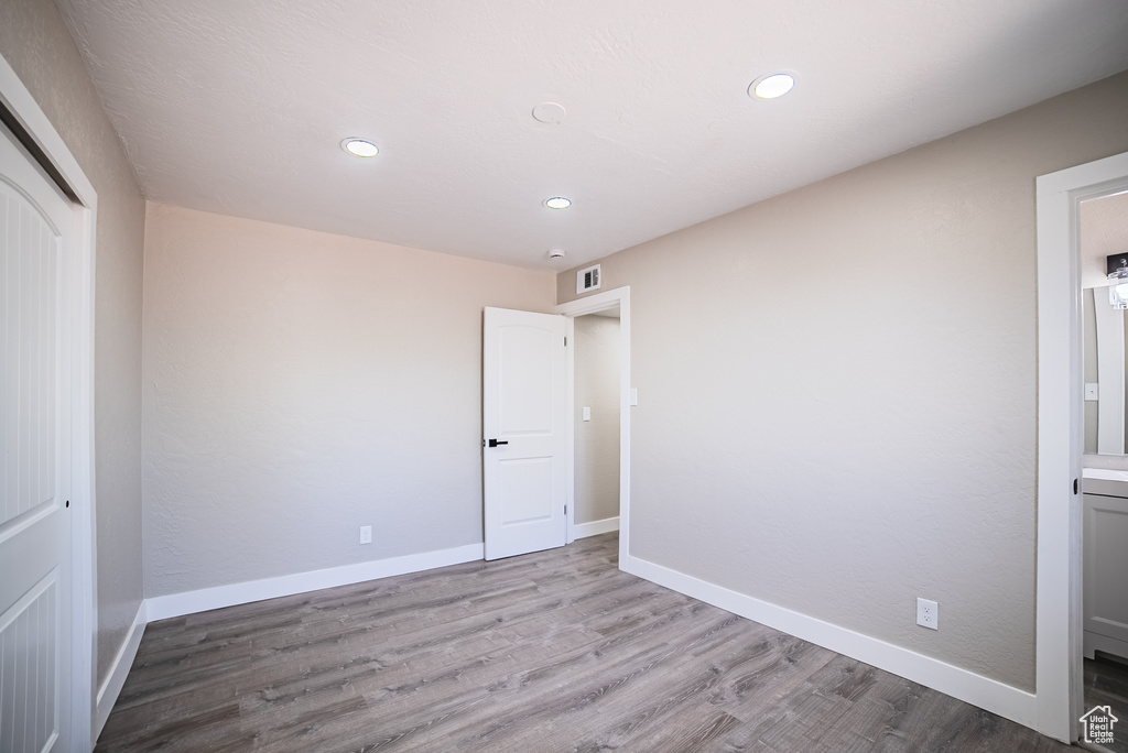 Unfurnished bedroom with wood finished floors, a closet, recessed lighting, and ensuite bath