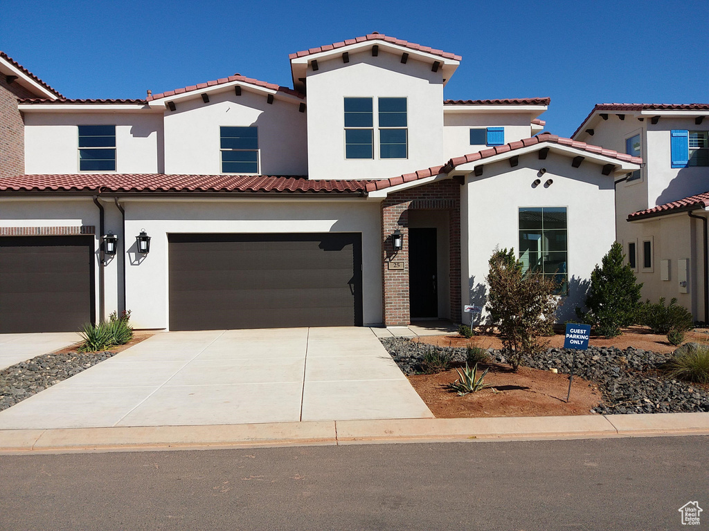 Mediterranean / spanish home featuring an attached garage, concrete driveway, stucco siding, and a tiled roof
