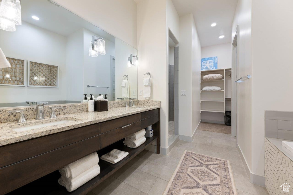 Full bath with double vanity, a spacious closet, tile patterned flooring, a tile shower, and recessed lighting
