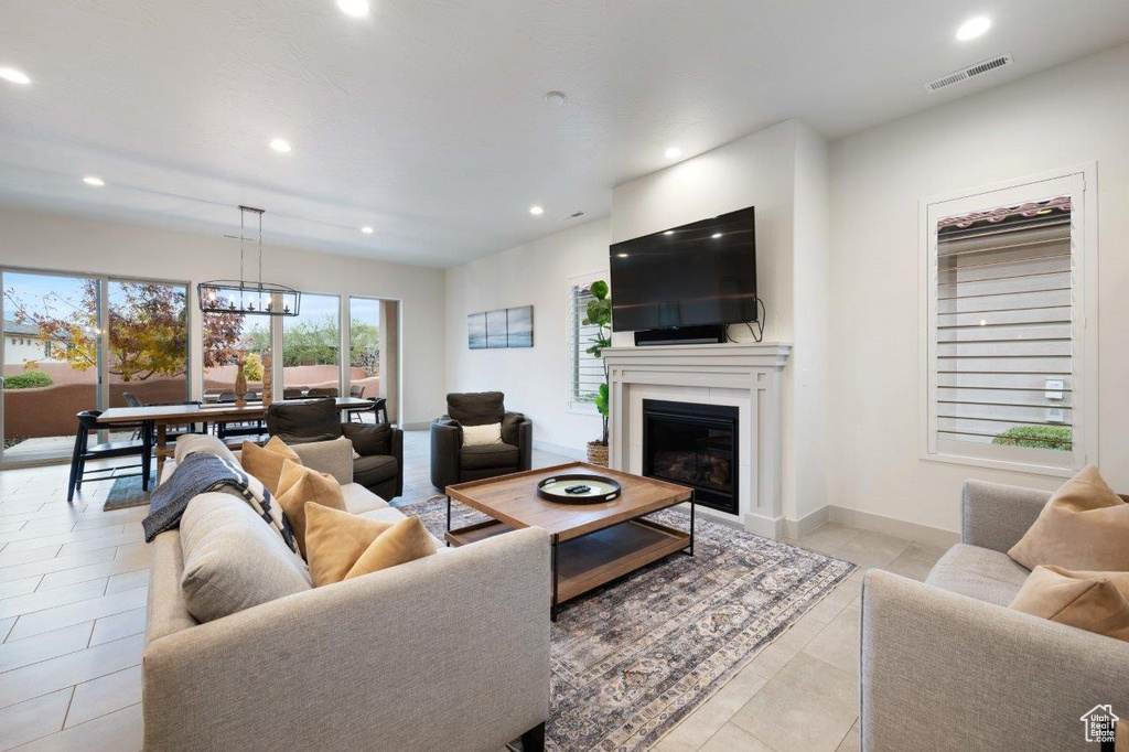 Living area featuring recessed lighting, a glass covered fireplace, a chandelier, and light tile patterned floors