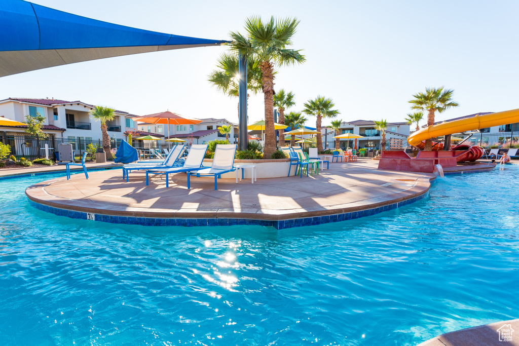 Community pool featuring a water slide, a patio, and a residential view