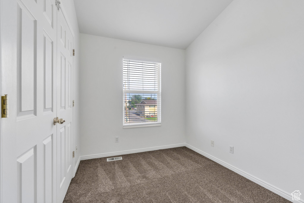 Unfurnished bedroom featuring dark colored carpet and baseboards