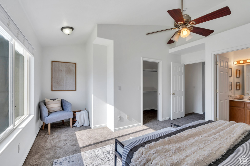 Bedroom featuring light colored carpet, vaulted ceiling, a spacious closet, connected bathroom, and multiple windows