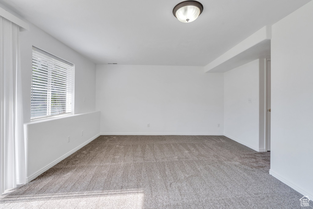 Spare room featuring carpet flooring and baseboards