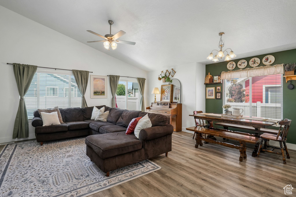 Living room featuring wood finished floors, a chandelier, ceiling fan, and high vaulted ceiling