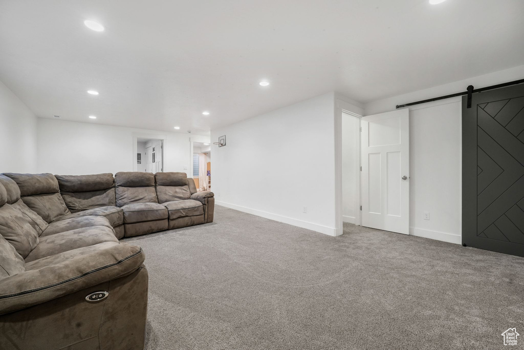 Carpeted living room featuring a barn door and recessed lighting