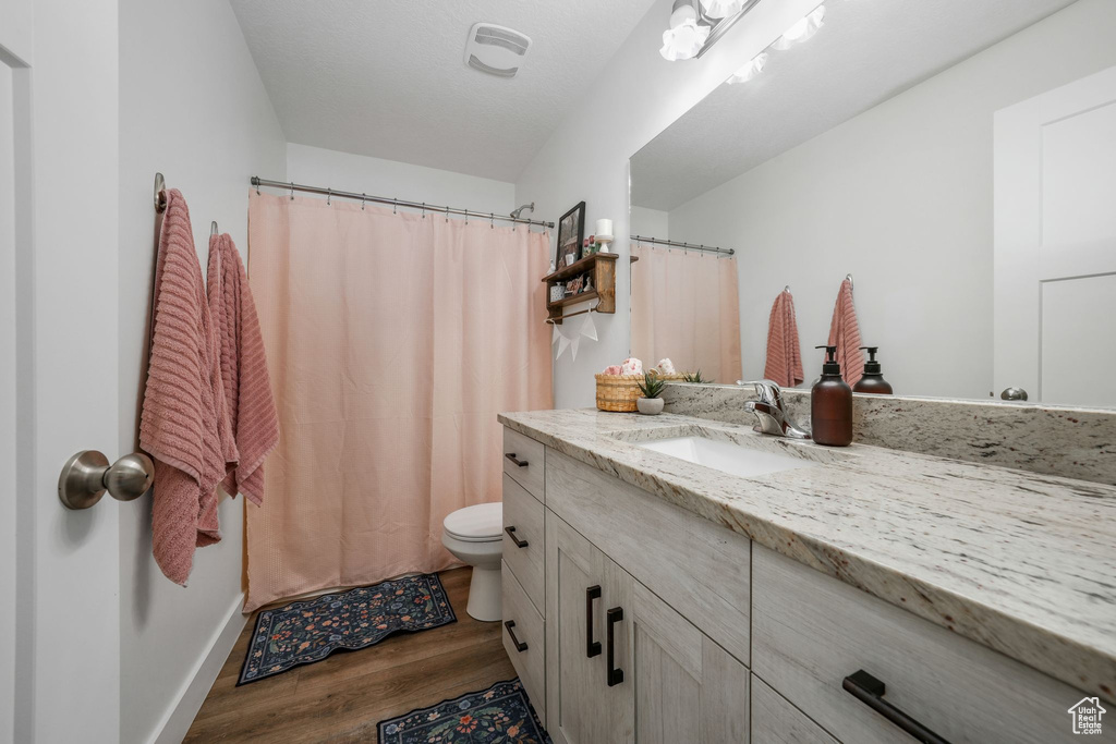 Full bath with vanity, wood finished floors, and curtained shower