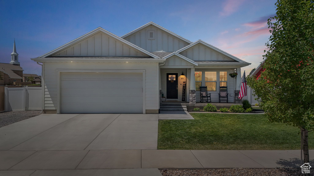 Craftsman-style house with board and batten siding, covered porch, a garage, and driveway