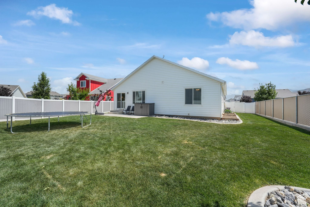 Back of property featuring a trampoline, a fenced backyard, and a patio area