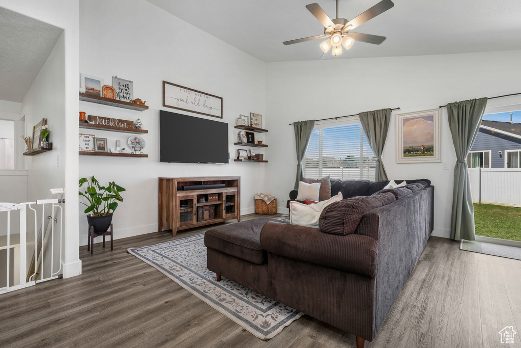Living area with wood finished floors, healthy amount of natural light, a ceiling fan, and vaulted ceiling