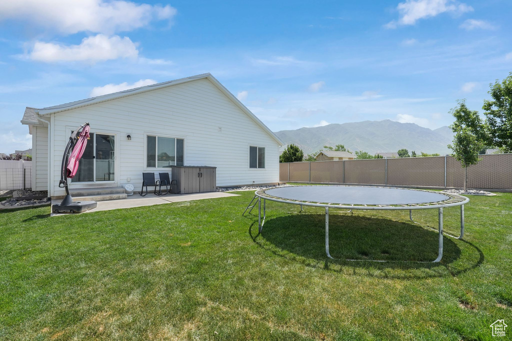 Back of house featuring a trampoline, a mountain view, and a patio area