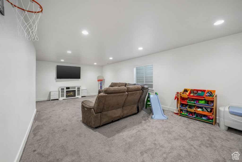 Living room featuring recessed lighting, carpet flooring, and a lit fireplace