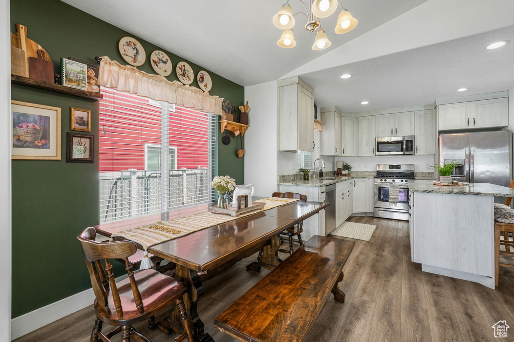 Dining space with a chandelier, lofted ceiling, dark wood-type flooring, and recessed lighting