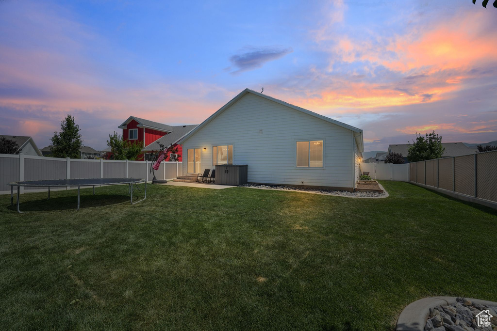 Back of house with a trampoline, a fenced backyard, and a patio