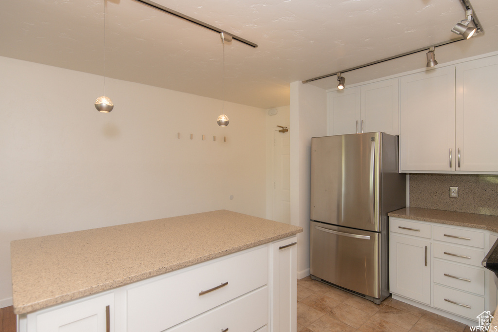 Kitchen featuring freestanding refrigerator, rail lighting, and white cabinets