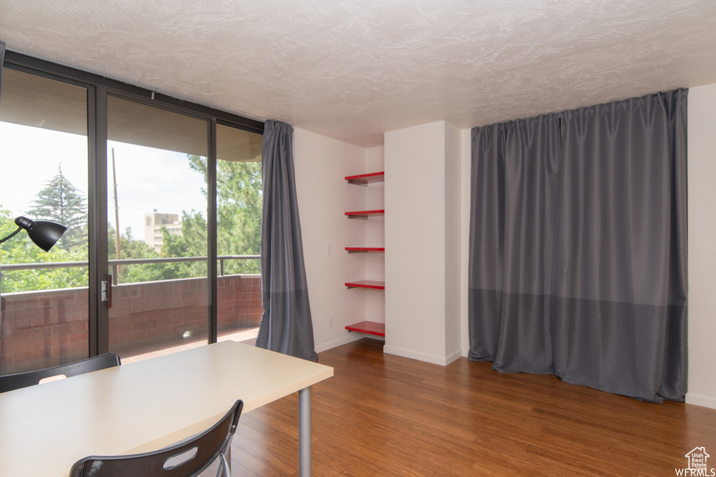 Office with wood finished floors, a textured ceiling, and expansive windows