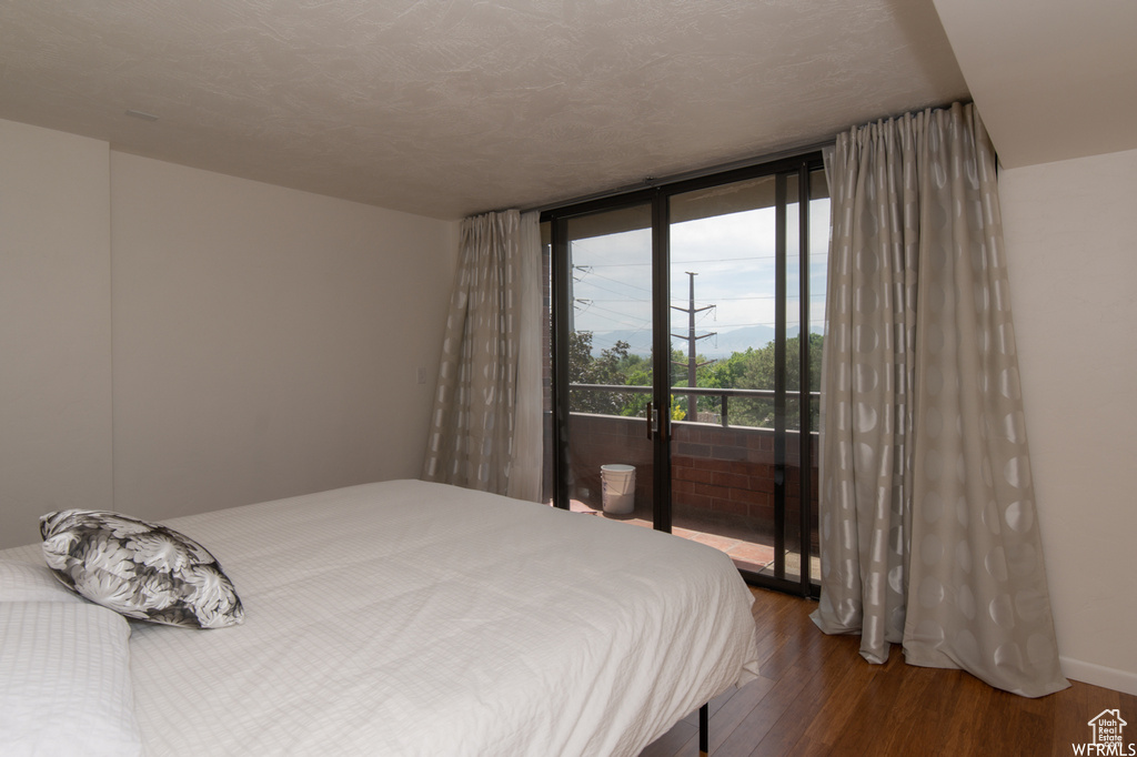 Bedroom with access to outside, wood finished floors, and expansive windows