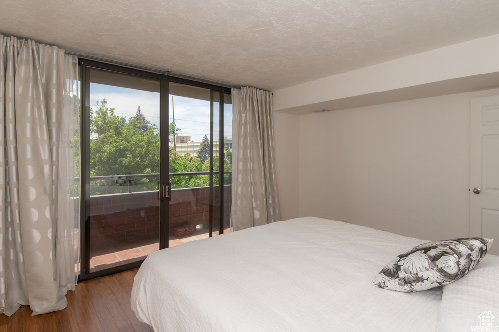 Bedroom with wood finished floors, access to outside, and expansive windows
