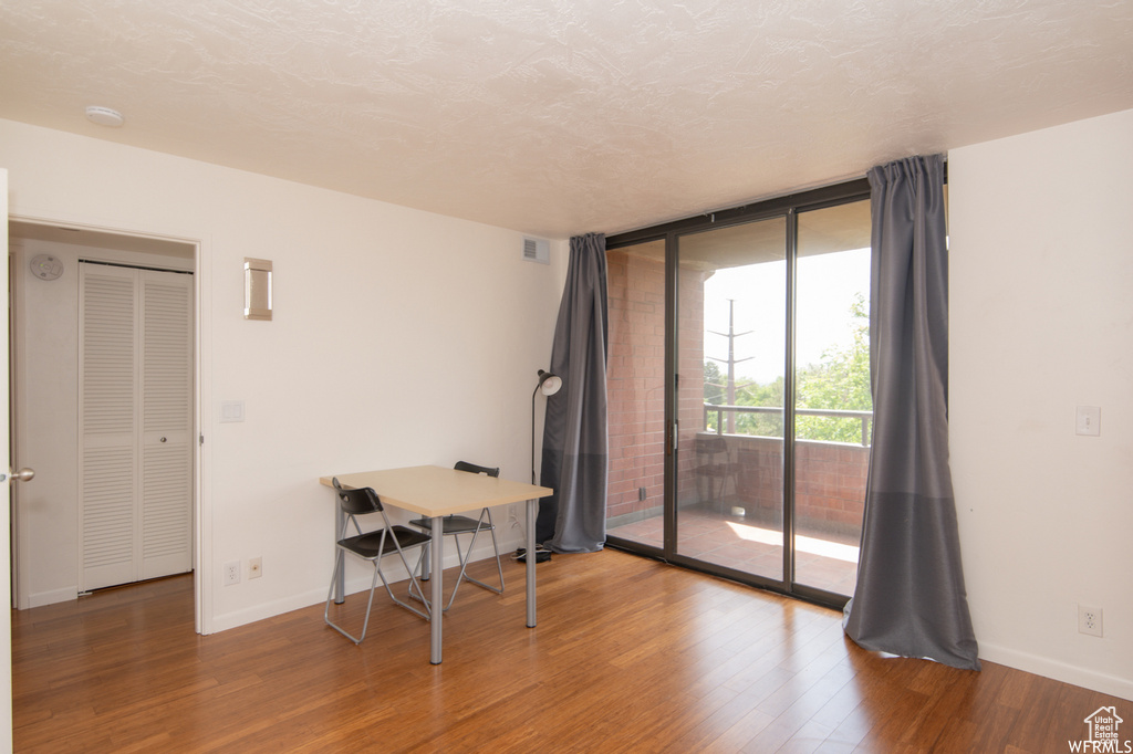Unfurnished room featuring wood finished floors, expansive windows, and a smoke detector