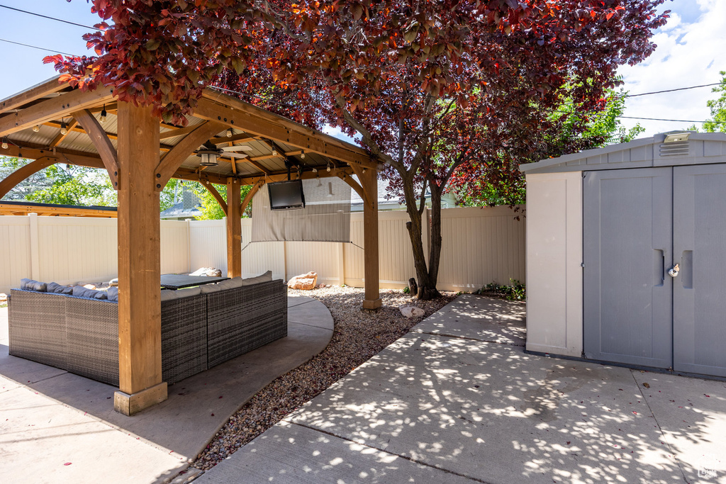 Fenced backyard featuring a gazebo, an outdoor hangout area, a patio, and a storage unit
