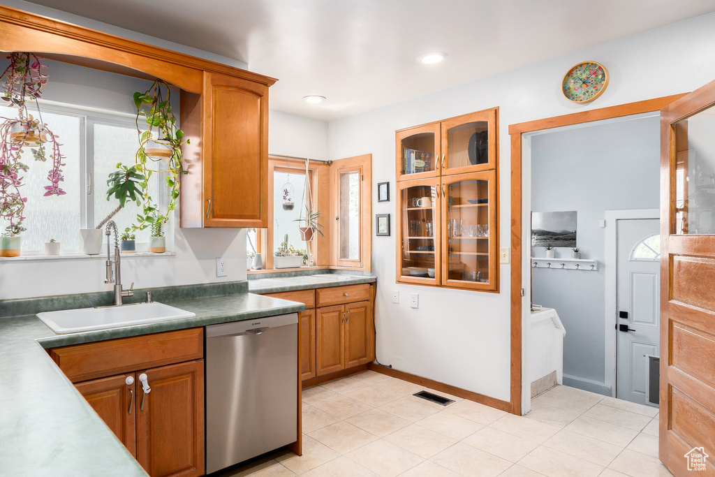 Kitchen featuring stainless steel dishwasher, brown cabinets, glass insert cabinets, light tile patterned flooring, and recessed lighting