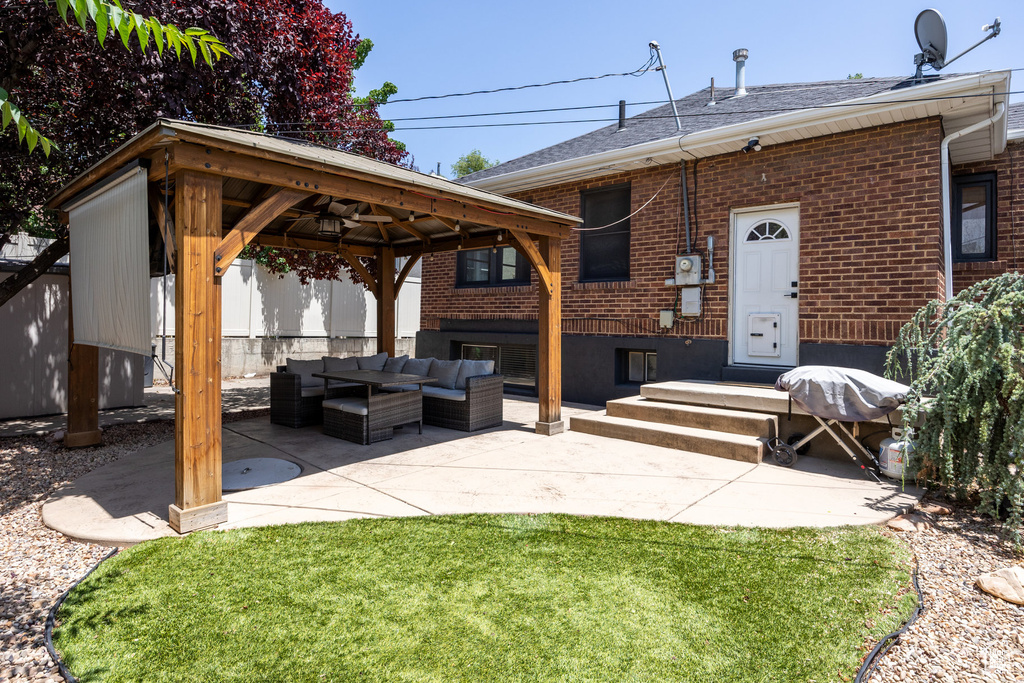 Back of house featuring outdoor lounge area, a gazebo, brick siding, a patio area, and a shingled roof
