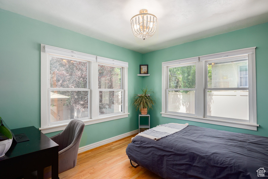 Bedroom featuring light wood-style floors, a chandelier, and a desk