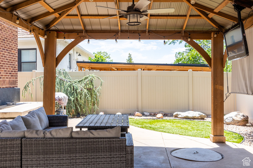 Fenced backyard featuring a gazebo, a patio, ceiling fan, and outdoor lounge area