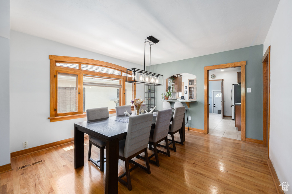 Dining space with arched walkways and light wood-style floors