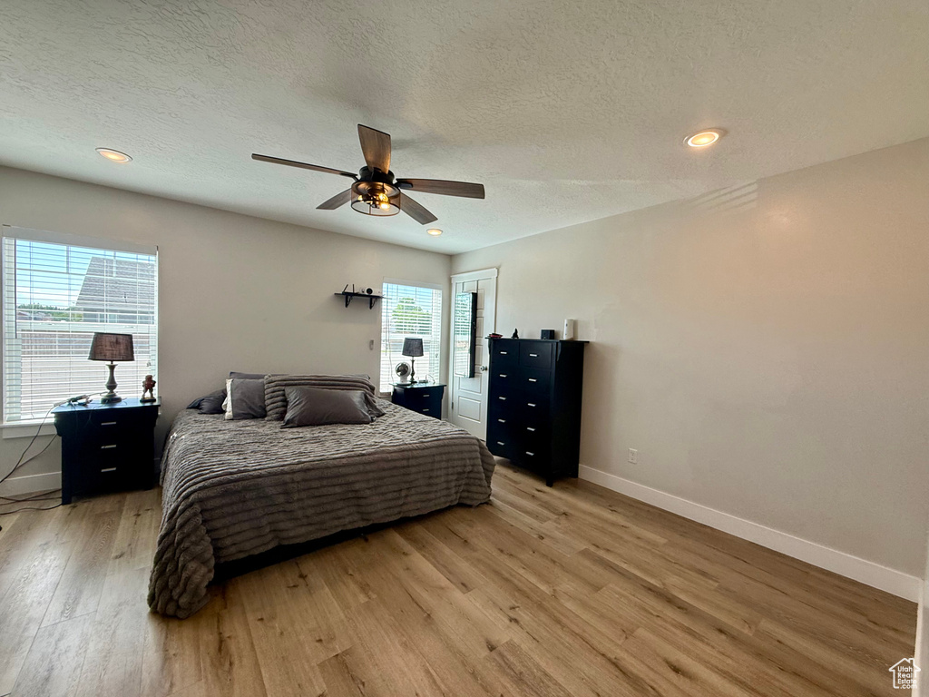 Bedroom with light wood-style floors, a textured ceiling, ceiling fan, and recessed lighting