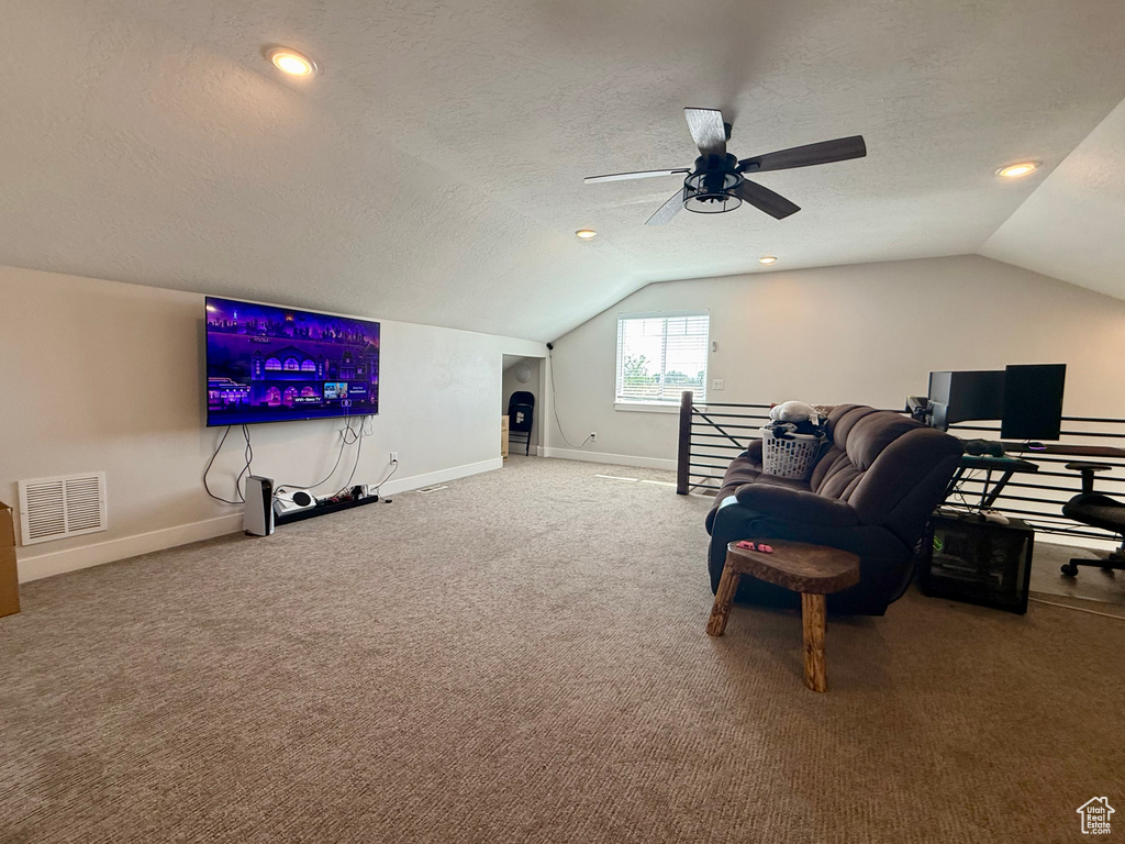 Interior space with vaulted ceiling, carpet, a textured ceiling, a ceiling fan, and an upstairs landing