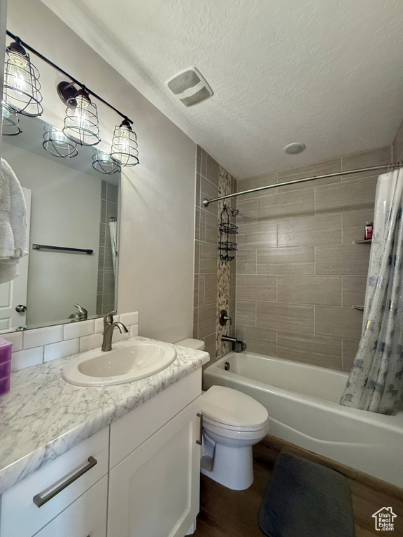 Bathroom featuring shower / bath combo, vanity, a textured ceiling, and wood finished floors