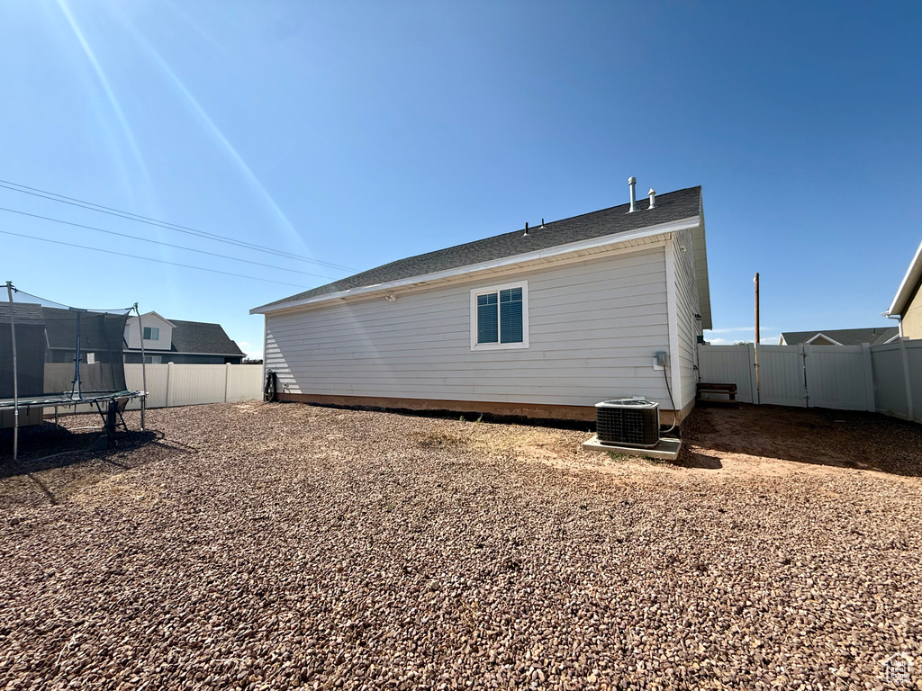 Rear view of house with a trampoline, a fenced backyard, and a gate