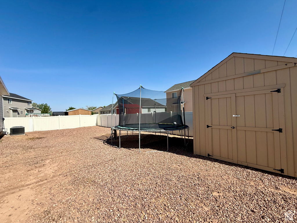 Fenced backyard featuring a storage unit and a trampoline