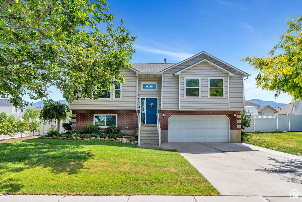 Bi-level home featuring a garage, driveway, and brick siding