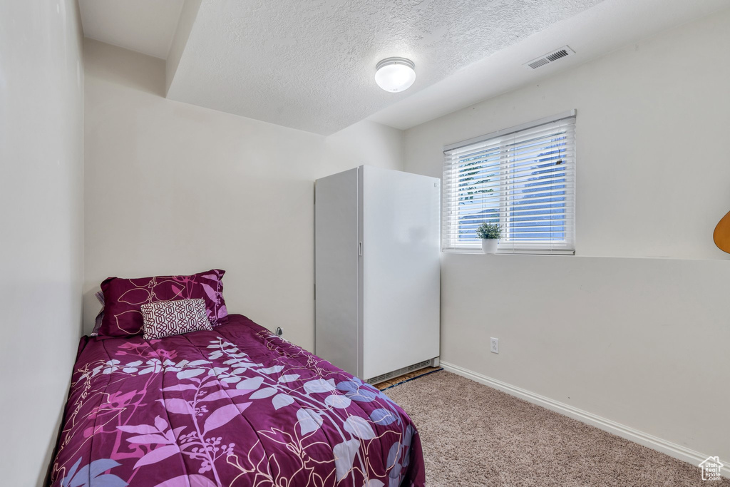 Carpeted bedroom with a textured ceiling and baseboards
