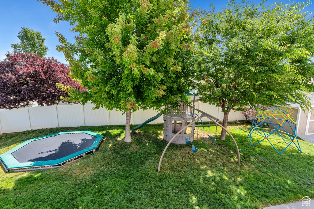 Fenced backyard with a trampoline and a playground