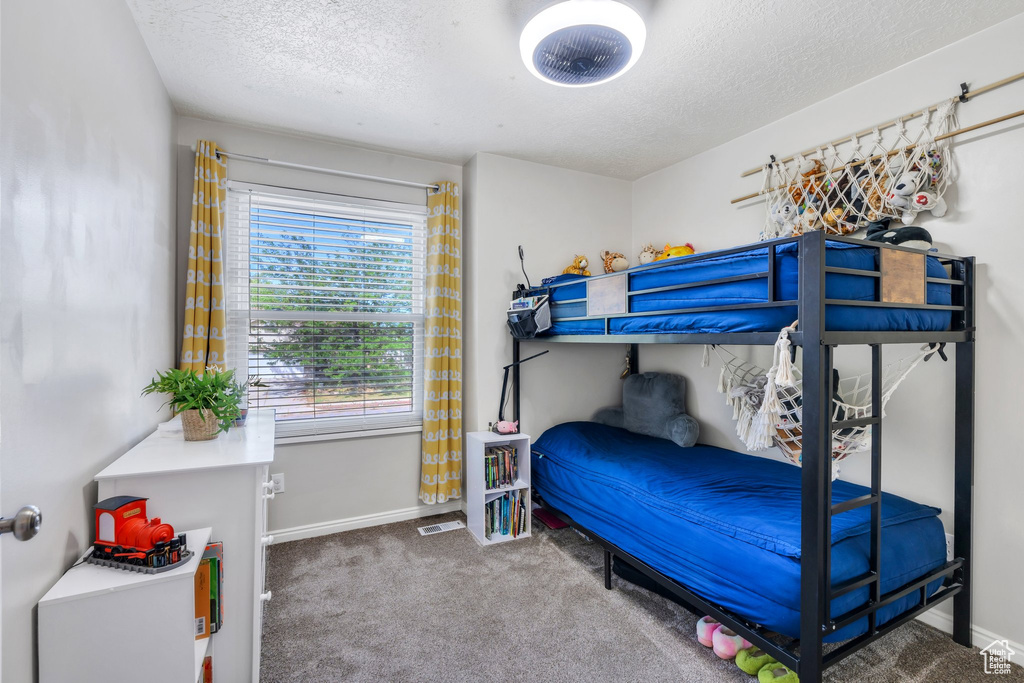 Carpeted bedroom featuring a textured ceiling and baseboards