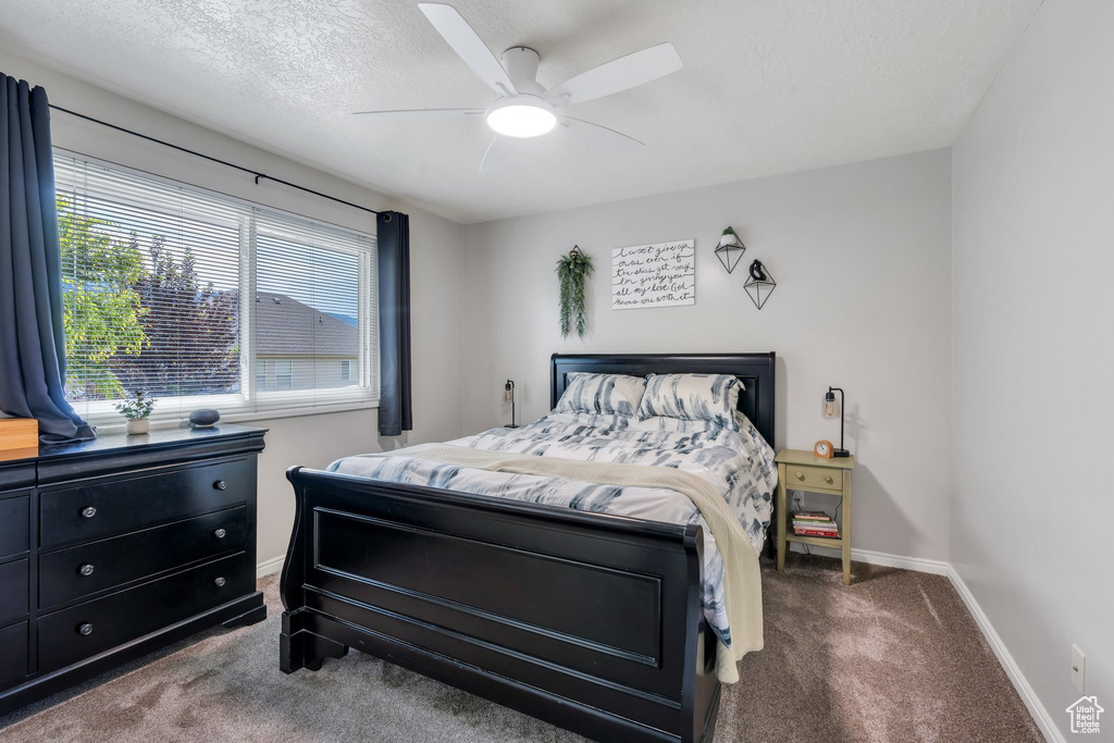 Carpeted bedroom with ceiling fan and a textured ceiling