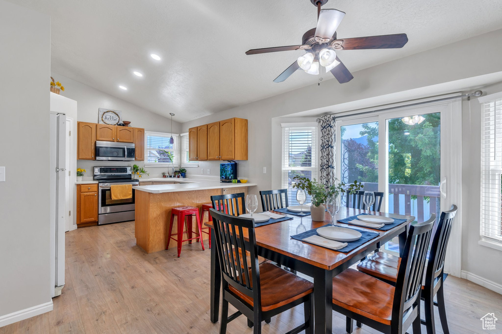 Dining room with light wood finished floors, a ceiling fan, vaulted ceiling, and recessed lighting