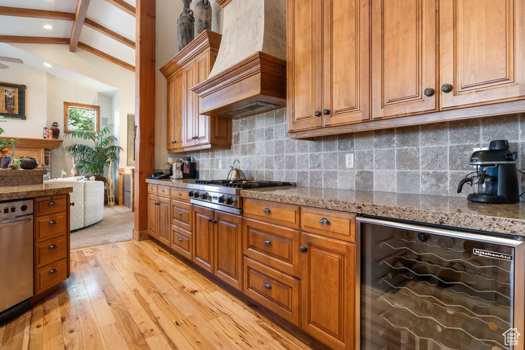 Kitchen featuring beverage cooler, custom exhaust hood, appliances with stainless steel finishes, light wood-style floors, and brown cabinetry