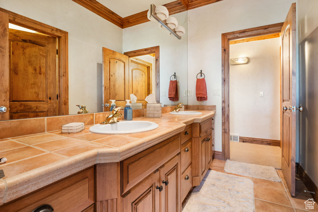 Full bath featuring double vanity, crown molding, and tile patterned flooring