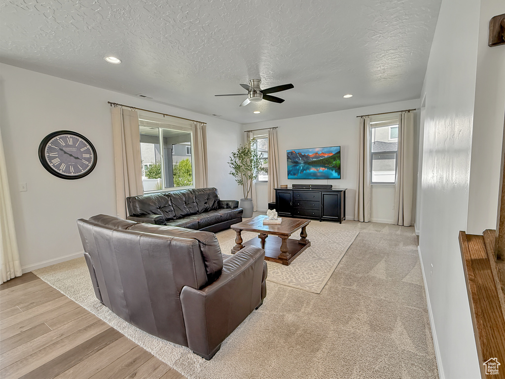 Living area featuring a ceiling fan, a textured ceiling, light wood-style flooring, and recessed lighting