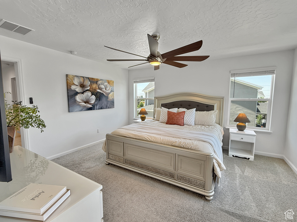 Carpeted bedroom with a ceiling fan and a textured ceiling