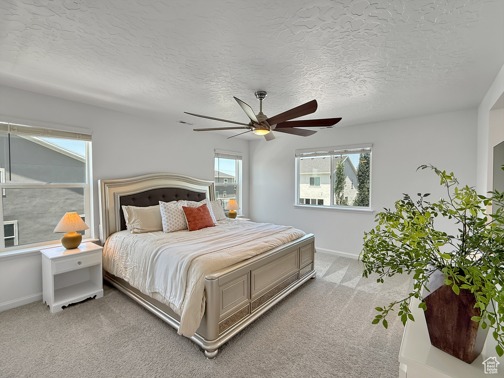 Bedroom with light colored carpet, a textured ceiling, and a ceiling fan